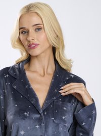 Marinblå sammet pyjamasset med silverstjärnor broderade, med slagkrage, bröstficka och knappstängning. Mjuk textur synlig.