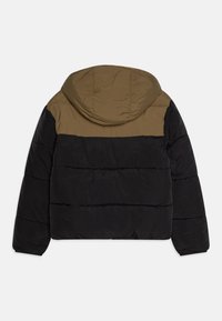 Giacca a vento imbottita con cappuccio, caratterizzata da un design a blocchi di colore; parte superiore in khaki, parte inferiore in nero e una texture trapuntata su tutta la superficie.