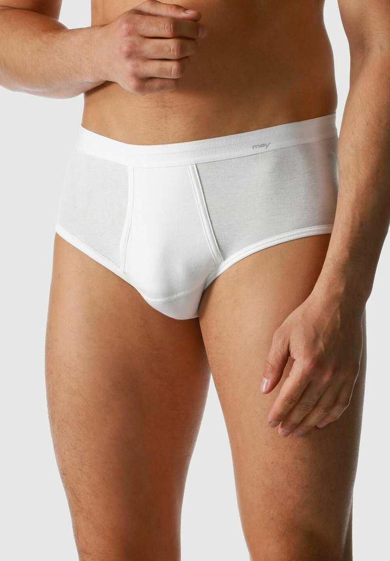Weiße Baumwollunterwäsche mit glatter Textur, elastischem Bund und einer engen Passform, die die Konturen des Beins und Körpers des Trägers betont.