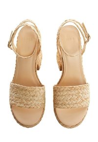 Sandales espadrilles tissées couleur tan avec un talon épais, présentant une large sangle tressée sur les orteils et une délicate bride à la cheville.