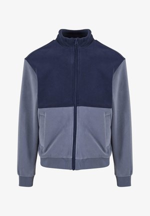 Tamsiai mėlynas ir šviesiai pilkas fliso užtrauktukas, su aukšta apykakle, pilnu priekiu užtrauktuku ir guminėmis rankogaliais bei apatine dalimi. Lygus paviršius, laisvas siluetas.