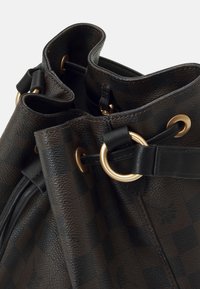 Brown leather drawstring bag with gold-tone hardware, textured surface, and a checkered pattern. Features dual side openings and soft edges.