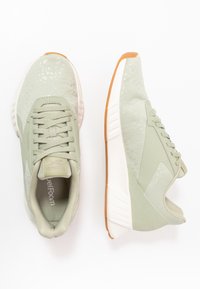 Světle zelené sportovní boty vyrobené z texturovaného materiálu s polstrovanou podrážkou. Vlastnosti zahrnují zaoblenou špičku, šňůrky a gumovou podrážku.