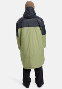 Long waterproof coat featuring a green body and dark blue upper section, with a hood and logo detail on the back. Made of smooth material.