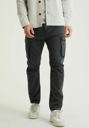 Zwarte cargobroek van katoen, met meerdere zakken, een slim fit en een subtiele textuur. Gepaard met witte sneakers.