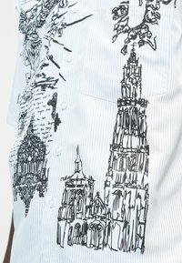 Hellblau gestreiftes Hemd mit schwarz skizzierten architektonischen Zeichnungen von hohen Kathedralentürmen und handgeschriebenem Text.