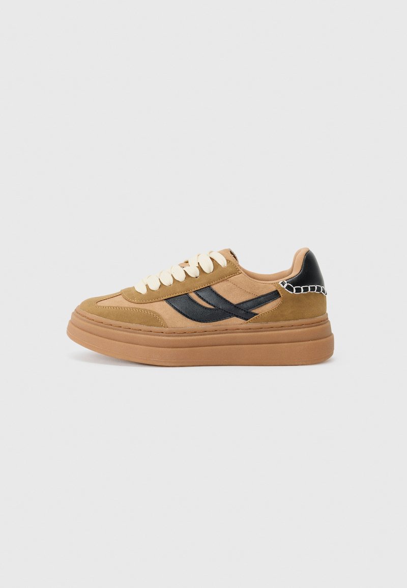 Baskets en suede marron avec accents noirs, bout rond, lacets beiges et une épaisse semelle en gomme. Présente un détail en chaîne sur le talon.