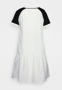 Robe blanche avec un design à manches courtes raglan noires, dotée d'un ourlet froncé et d'une texture lisse, mettant en valeur un schéma de couleurs bicolore.