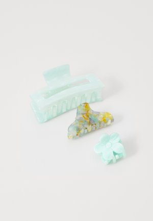 Set di tre fermagli per capelli: materiale traslucido verde menta, uno rettangolare, uno a forma di fiore e uno beige marmorizzato con accenti gialli.