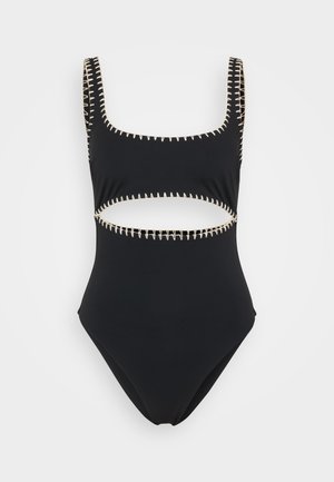 Maillot de bain une pièce noir avec des bretelles larges, présentant des découpes sur les côtés et des coutures beige contrastantes le long de l'encolure et des découpes.
