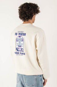 Felpa color crema con una grafica sul retro che presenta un'illustrazione di una pianta e il testo "NON DIMENTICARE DI BERE LE TUE PIANTE."