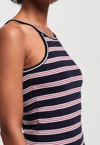 Marineblauw tanktop met rode en witte horizontale strepen, met een aansluitend ontwerp en contrasterende zwarte bies langs de halslijn en armsgaten.