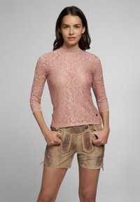 Rosa Spitzentop mit hohem Kragen und Dreiviertelärmel, kombiniert mit beigen Shorts mit floraler Stickerei und Taschen.