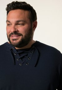 Námořnická modrá košile s šněrovacím výstřihem se stříbrnými očky, vyrobená z měkké tkaniny, s hladkým povrchem a volným střihem.