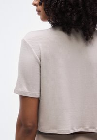 Haut à manches courtes côtelé beige clair avec un design court, doté d'une texture douce et d'un détail subtil à l'ourlet.