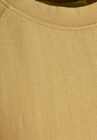Felpa girocollo di colore senape chiaro, con colletto a coste e texture liscia. Il tessuto appare morbido e leggermente texturizzato.