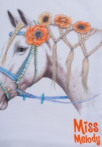 Maglietta bianca con un'illustrazione dettagliata di un cavallo decorato con fiori arancioni e capelli intrecciati, con dettagli di imbracatura blu e verde.