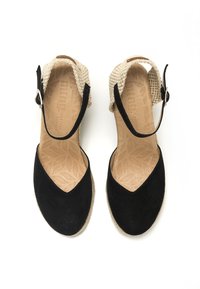 Zapatos de esparto negro de ante con una correa de tobillo tejida beige y hebilla ajustable. Plantilla de textura natural con un patrón de hojas.