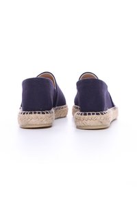 Espadrilles de lona azul marino con suela de yute trenzado y parte trasera. Textura suave, forma redondeada y diseño minimalista.