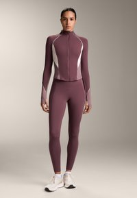 Hosszú ujjú, cipzáras sportdzseki és hozzá illő leggings gazdag bordó színben, világos szürke panel kiegészítőkkel és sima, rugalmas anyagból.