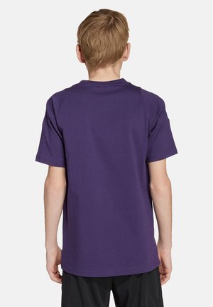 T-shirt en coton violet à manches courtes et col rond ; texture lisse, coupe décontractée, et sans logos ni motifs visibles au dos.