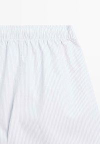 Spodnie od piżamy w niebiesko-białe paski, z elastycznym pasem i miękką fakturą tkaniny. Pionowe cienkie paski na całej powierzchni.