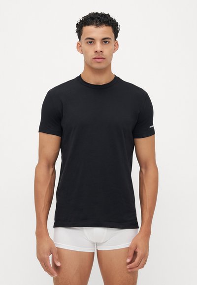 Schwarzfarbiges T-Shirt mit Rundhalsausschnitt in einer schmalen Passform, aus weichem Stoff; kurze Ärmel und ein dezentes Logo-Detail am linken Arm.