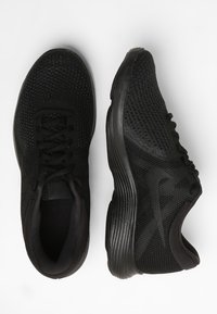 Svarta träningsskor med en texturerad mesh-överkonstruktion, rund tå, snörning och en vadderad sula med en subtil böjd design.