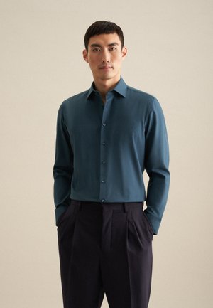 Donkerblauwe, lange mouwen shirt met een aansluitend ontwerp, met knoopsluiting en contrasterende donkere knopen, gecombineerd met donkere, geplooide broek.