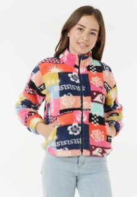 Farverig fleecejakke med lynlås, der har et patchwork-design med blomster- og geometriske mønstre i pink, blå, gul og sort.
