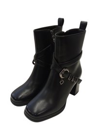 Stivaletti neri alla caviglia in pelle liscia, con punta quadrata, tacco robusto e fascia decorativa con un ciondolo a forma di cuore argentato.