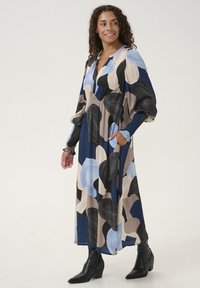 Long, multicolored dress featuring large abstract shapes in blue, black, and beige. Fabric is lightweight with a flowy design and pockets.