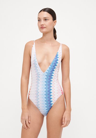 Eénstuk zwempak met een diepe V-hals. Heeft een zigzagpatroon in blauw, oranje en roze op een witte achtergrond. Gladde textuur.
