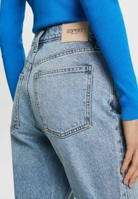Jeans in denim azzurro chiaro con lavaggio sbiadito, dotati di un'etichetta in pelle marrone con la scritta "ESPRIT NEW YORK" e doppie tasche posteriori.