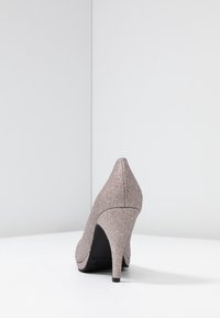 Zapato de tacón alto en un material dorado rosa brillante, con puntera puntiaguda y un diseño elegante. Presenta un acabado texturizado y una suela negra delgada.