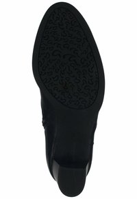 Semelle de chaussure en cuir noir avec un motif de grip en caoutchouc texturé, dotée d'un talon bas et d'un design à bout arrondi pour la stabilité et le confort.
