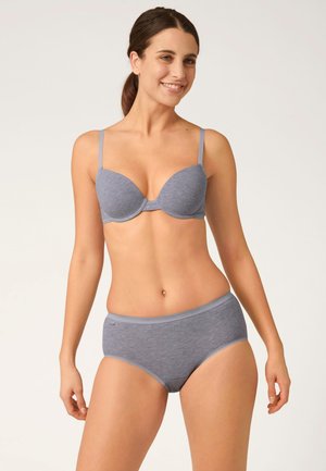 Woman smiling, wearing matching gray bra and briefs, standing against a plain light background.