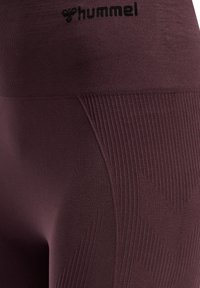 Leggings sportivi bordeaux con texture a coste e dettaglio logo in vita, progettati per flessibilità e comfort durante l'allenamento.