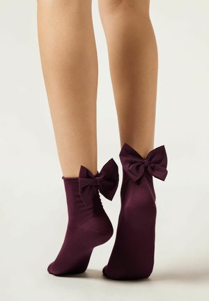 Burgundy ankle socks with a soft, smooth texture featuring large bows at the cuffs. The design highlights a fitted shape and snug fit.