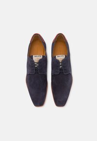 Scarpe in suede blu navy con un design elegante, dotate di punta affusolata, chiusura con lacci e fodera in pelle. I colori di accento includono il rosso sul tallone.