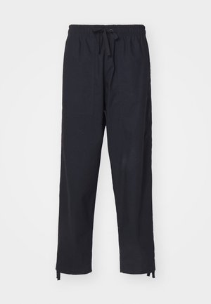 Pantalon décontracté noir avec taille élastique, cordon de serrage à l'avant, deux poches avant et liens réglables aux chevilles, présenté sur fond blanc.