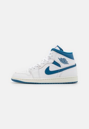 White mid-top sneakers with blue accents, featuring a leather material, perforated toe box, and a textured rubber sole. Iconic branding on the sides.