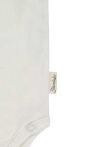 White baby bodysuit corner with snap button and small fabric label showing "Sterntaler" brand name.