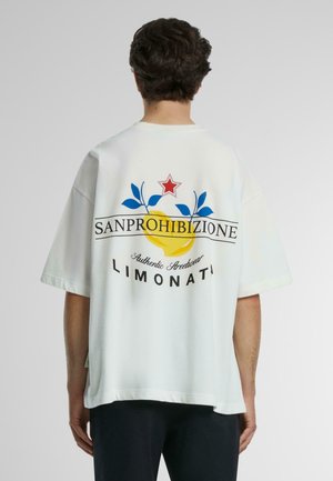 Weißes übergroßes T-Shirt mit einem bunten Grafikdesign auf der Rückseite: ein gelber Kreis, blaue Blätter und ein roter Stern mit dem Text "SANPROHIBIZIONE."