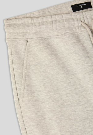 Pantaloni sportivi grigi chiari realizzati in materiale morbido e testurizzato, con vita elastica e cordoncino. Presentano tasche laterali e l'etichetta del marchio.