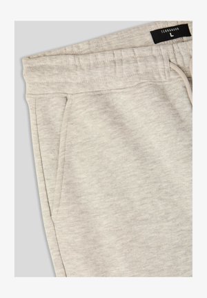 Pantaloni sportivi grigi chiari realizzati in materiale morbido e testurizzato, con vita elastica e cordoncino. Presentano tasche laterali e l'etichetta del marchio.