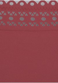 Roter Stoff mit strukturierter Rippung, versehen mit einem dekorativen Streifen aus ausgeschnittenen geometrischen Formen am oberen Rand. Glatte Oberfläche, weiche Textur.