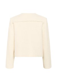 Giacca di colore crema, con texture e design cropped, dotata di maniche lunghe. Presenta un orlo leggermente sfilacciato lungo il giogo posteriore.