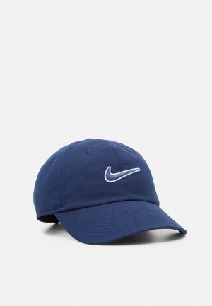 Navyblå Nike baseballkasket med hvidt broderet swoosh-logo og buet skygge på en ensfarvet lys baggrund.
