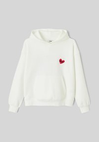Sweat-shirt blanc à capuche, avec un petit écusson en forme de cœur rouge sur la poitrine gauche. Tissu texturé et poche kangourou à l'avant.